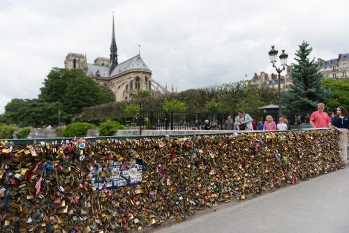 Lock-encrusted bridge in Paris, with Notre Dame in the background.