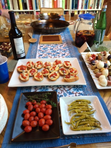 Anchovy toasts are in the background. The peppers are Spanish piparras.